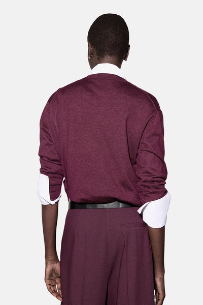 Pull à col rond bordeaux de MANGO, porté sur une chemise blanche avec un pantalon et une ceinture noirs, vue de dos.