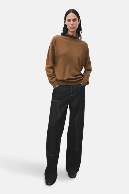 Pull à col roulé brun de MANGO, porté avec un jean ample foncé et des chaussures noires.