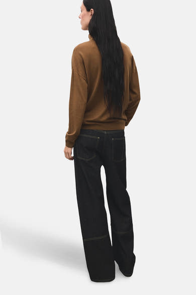 Pull à col roulé brun de MANGO, porté avec un jean large brut, vue de dos.