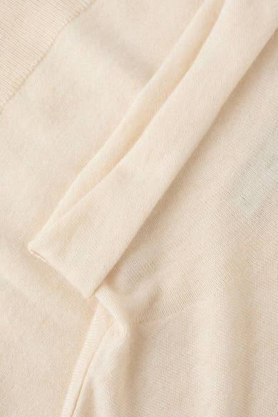 Pull à col roulé écru de MANGO, en maille fine texturée, avec une manche repliée.
