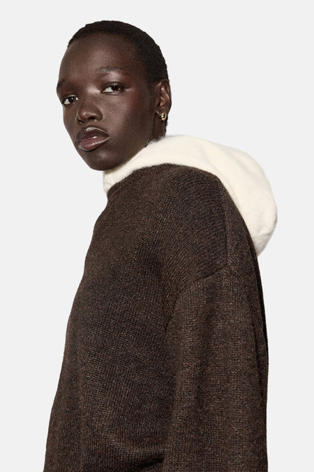 Bruine trui met ronde hals van MANGO, met contrasterende witte capuchon, gedragen met een wijde witte broek.