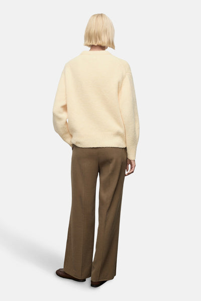 Pull à col rond jaune van MANGO, porté avec un pantalon marron à jambes larges, vue de dos.