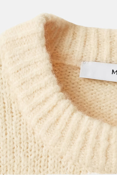 Pull à col rond jaune par MANGO, en tricot côtelé texturé, avec étiquette de marque visible.
