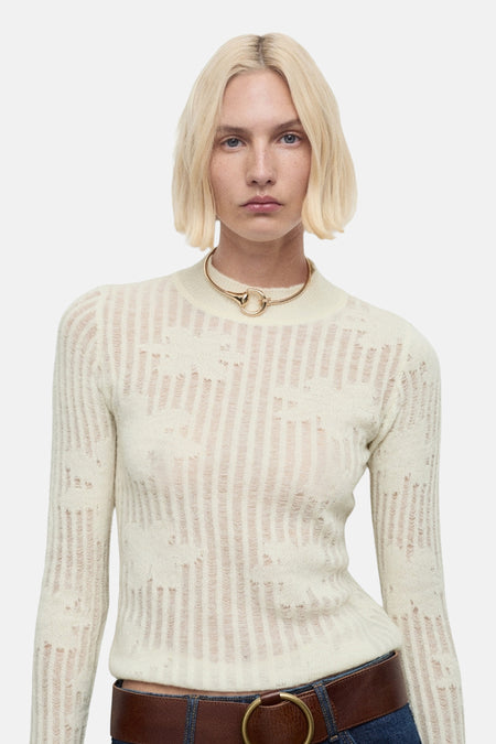 Beige ronde hals trui, van MANGO, met opengebreid patroon gedragen met een spijkerbroek en een bruine riem.