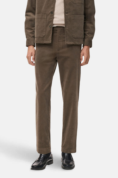 Pantalon marron en velours côtelé de MANGO, porté avec une veste et des mocassins noirs.
