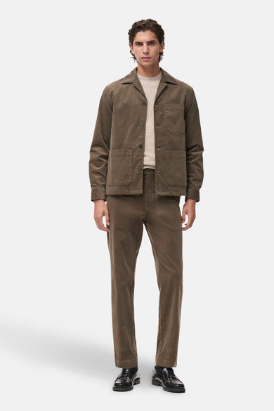 Pantalon de saison brun par MANGO, en velours côtelé, porté avec une veste assortie et des mocassins noirs.