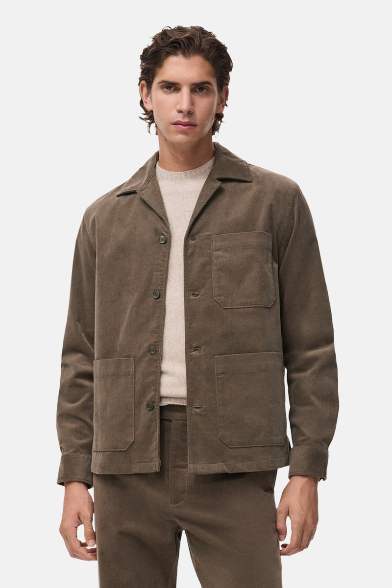 Chemise à manches longues grise de MANGO, avec poches plaquées et en velours côtelé, portée sur un pull beige.
