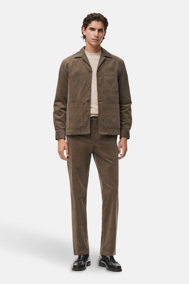 Chemise à manches longues grise de MANGO, portée avec un t-shirt beige et un pantalon en velours côtelé marron.