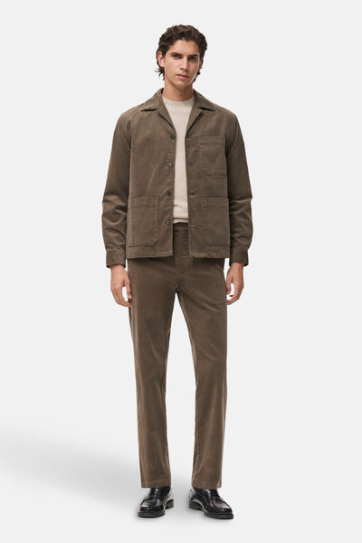 Chemise à manches longues grise de MANGO, portée avec un t-shirt beige et un pantalon en velours côtelé marron.