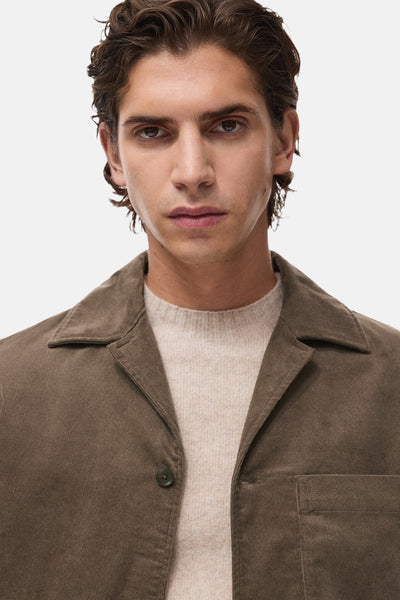 Chemise à manches longues grise de MANGO, en velours côtelé avec col classique et pull beige en dessous.