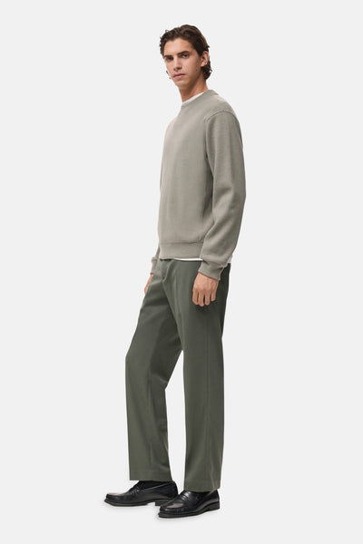 Sweat-shirt gris, col rond par MANGO, porté avec un pantalon vert olive et des mocassins noirs.