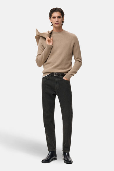 Pull à col rond beige de MANGO, porté avec un jean noir, une ceinture noire et des bottines noires.