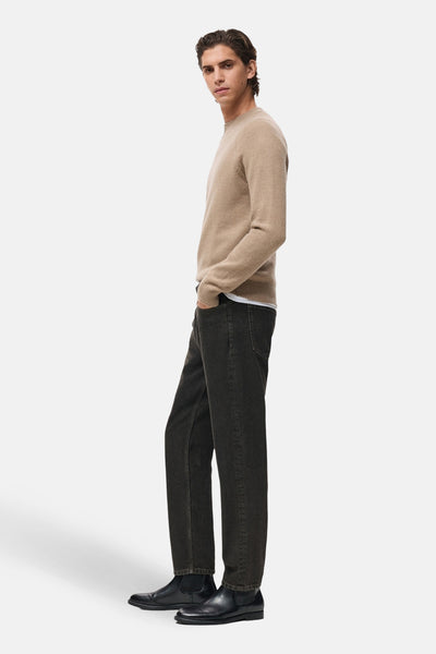 Pull à col rond beige de MANGO, porté avec un t-shirt blanc et un jean foncé avec des bottines noires.