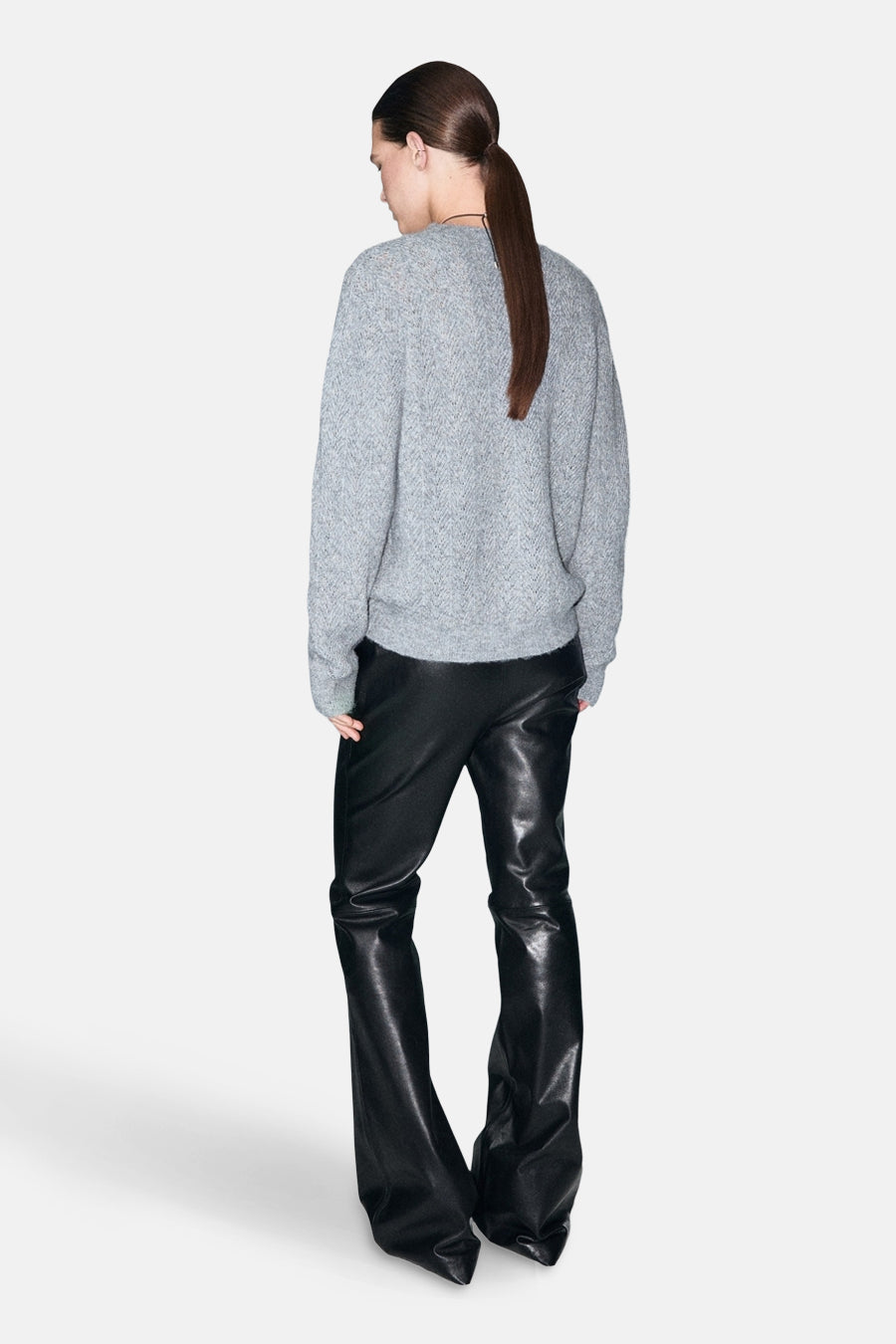 Pull à col rond bleu de MANGO, porté avec un pantalon en cuir noir, vue de dos.
