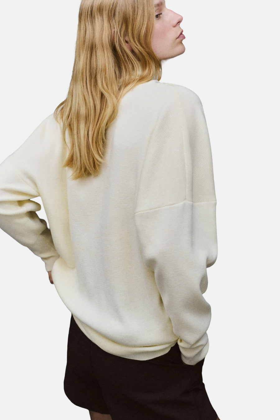 Pull à col roulé écru de MANGO, en maille texturée, porté avec un short noir.