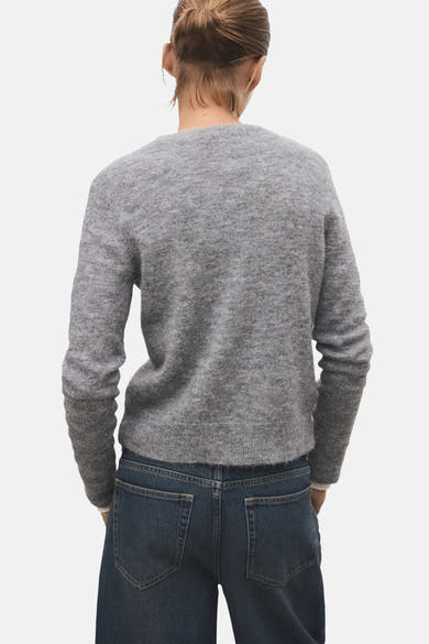 Pull à col rond gris de MANGO, porté avec un jean bleu foncé, vue de dos.
