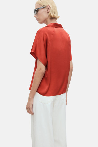 Oranje blouse met korte mouwen van MANGO, gedragen met een wijde witte broek, achtergezicht.