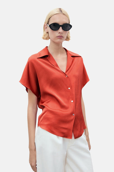 Oranje blouse met korte mouwen van MANGO, met klassieke kraag en witte knopen, gedragen met een witte broek.