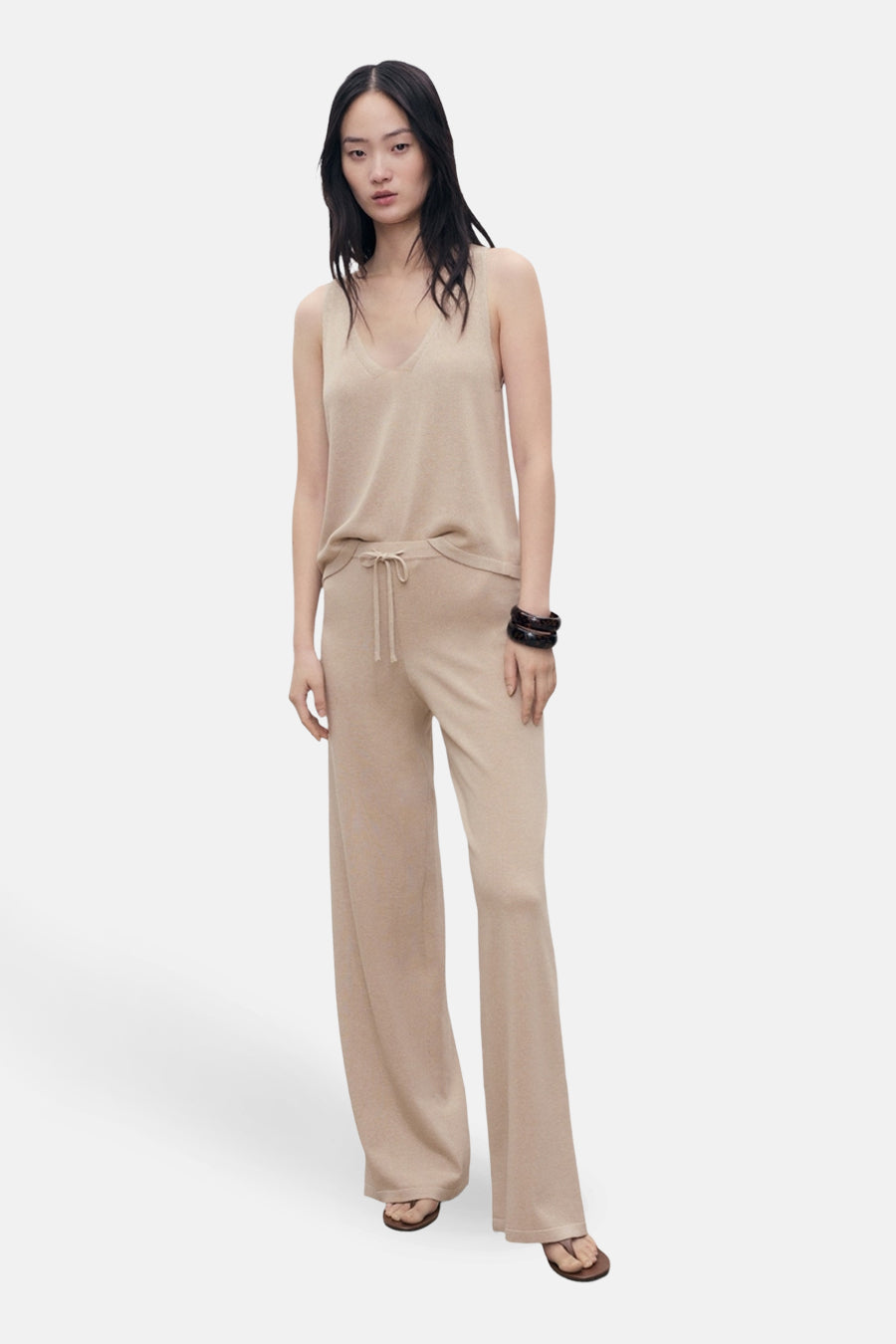 Débardeur beige de MANGO, porté avec un pantalon assorti à taille élastique, et un bracelet foncé.