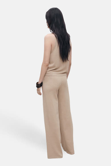 Débardeur beige by MANGO, porté avec un pantalon palazzo et des bracelets foncés.