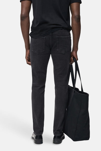 Donkergrijze spijkerbroek van MANGO, achterkant, gedragen met een zwart T-shirt en een zwarte tote bag.