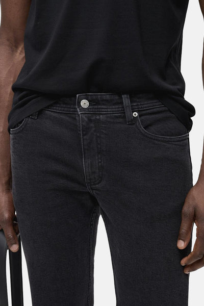Jean slim en denim gris foncé de MANGO, porté avec un t-shirt noir uni.
