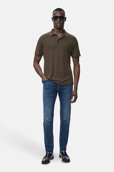 Middelblauwe spijkerbroek van MANGO, gedragen met een bruin poloshirt en zwarte loafers.