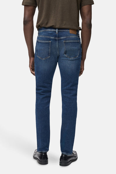 Middelblauwe spijkerbroek van MANGO, met achterzakken en gedragen met zwarte schoenen.