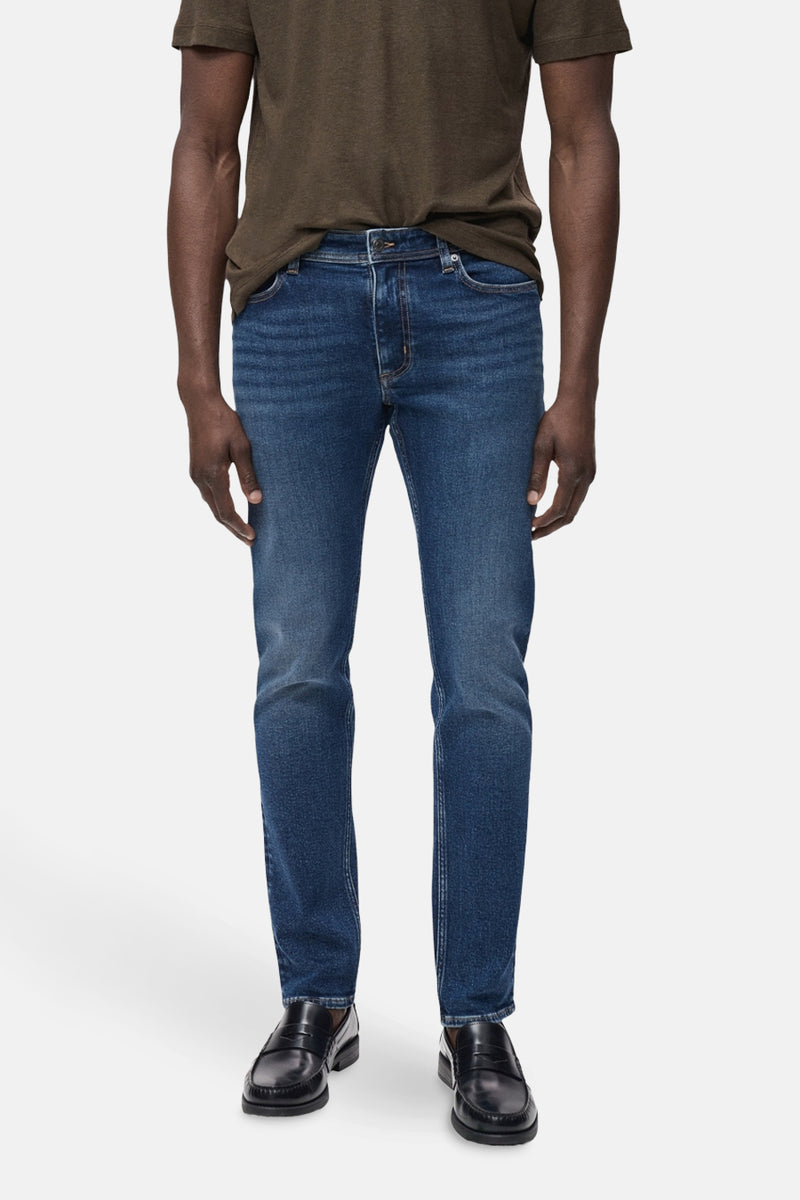 Middenblauwe spijkerbroek van MANGO, gedragen met een bruin T-shirt en zwarte loafers.