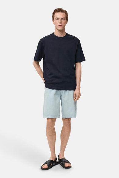 Donkerblauwe T-shirt met korte mouwen van MANGO, gedragen met een spijkerbroekshort en zwarte sandalen.