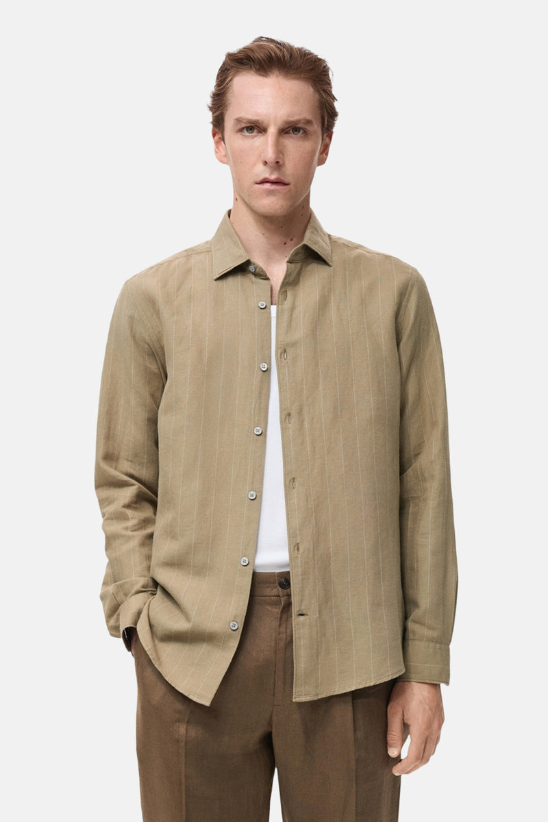 Kaki overhemd met lange mouwen van MANGO met verticale strepen, gedragen over een wit T-shirt.