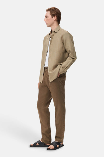 Chemise kaki à rayures verticales de MANGO, portée avec un t-shirt blanc et un pantalon marron.