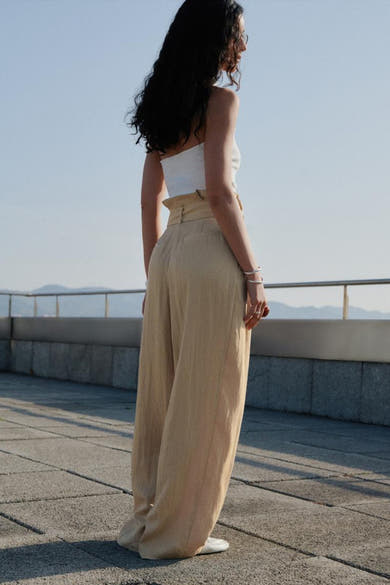 Beige broek van MANGO, wijde pasvorm met hoge taille, gedragen met een witte bandeau top.