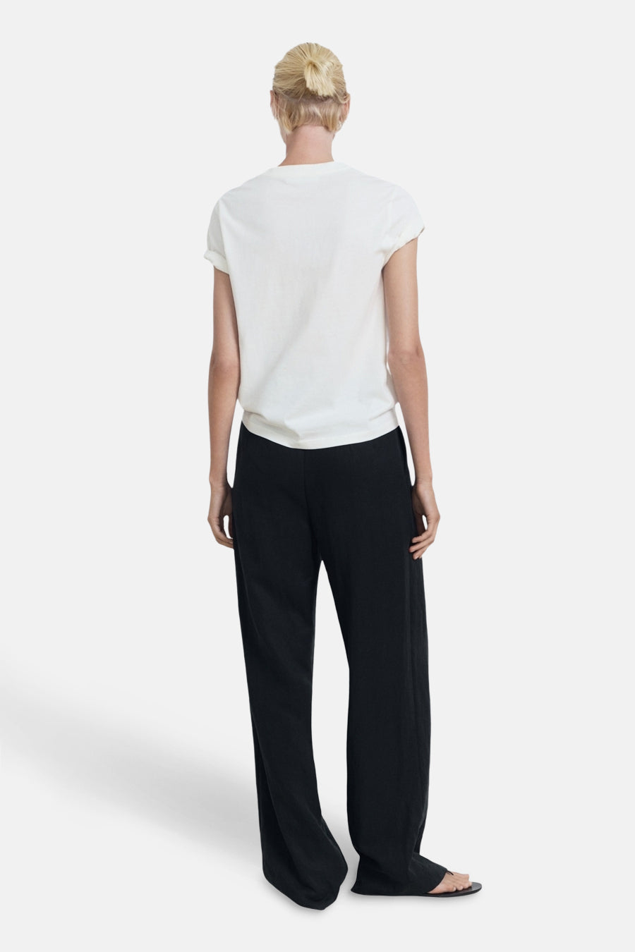 Wit T-shirt met korte mouwen van MANGO, gedragen met een zwarte, losvallende broek, achtergezicht.