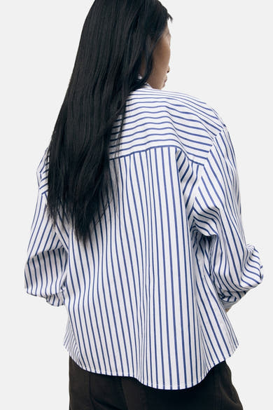 Chemise à manches longues rayée bleu et blanc de MANGO, vue de dos, avec cheveux longs noirs.