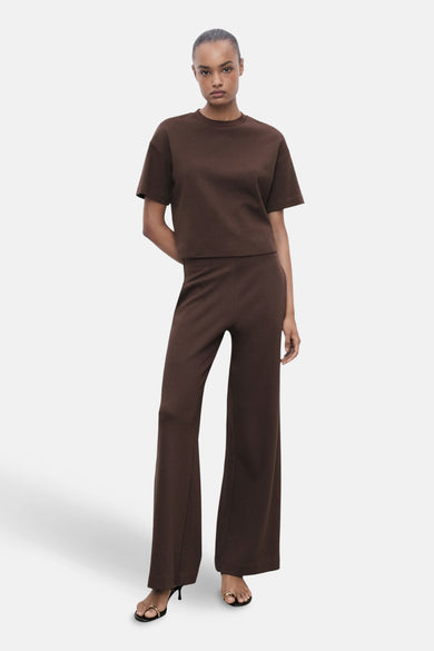 T-shirt brun à manches courtes de MANGO, porté avec un pantalon large assorti et des sandales à talons.