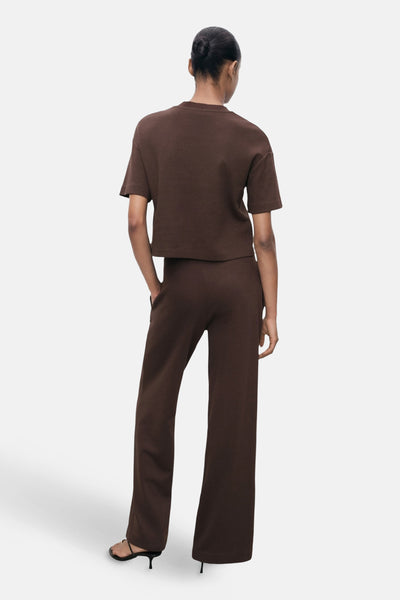 Effenchemise met korte mouwen in effen bruin van MANGO, gedragen met een bijpassende broek en hakken. Achterzicht.