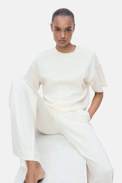 T-shirt écru à manches courtes de MANGO, porté avec un pantalon blanc assorti.