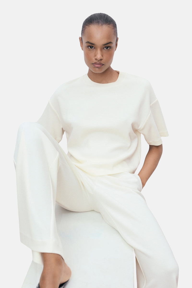 T-shirt écru à manches courtes de MANGO, porté avec un pantalon blanc assorti.