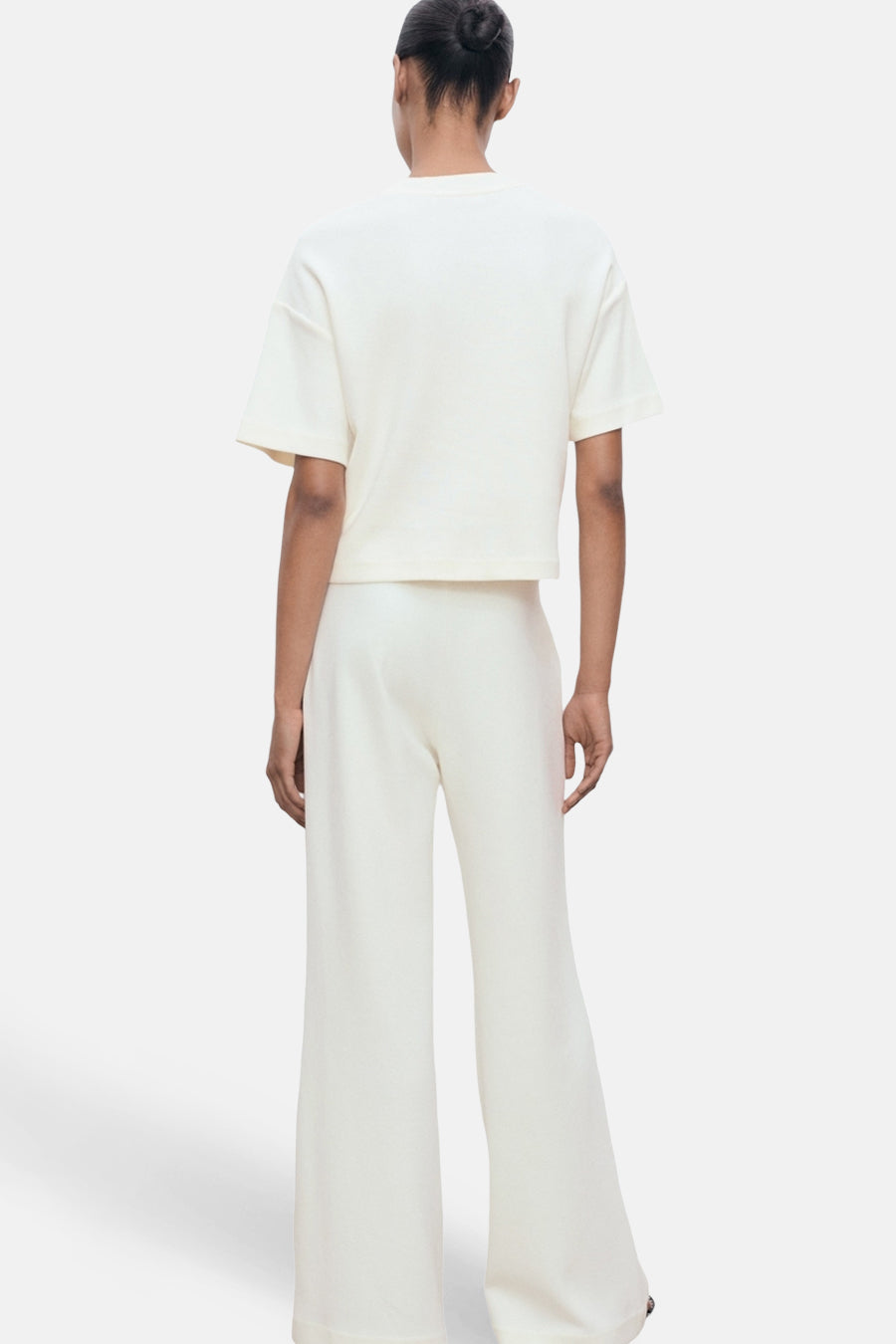 T-shirt écru à manches courtes de MANGO, porté avec un pantalon ample blanc, vue de dos.
