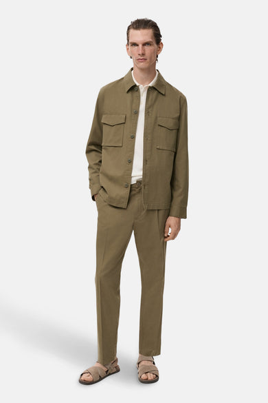Pantalon kaki de MANGO, porté avec une chemise et des sandales assorties pour un look décontracté.
