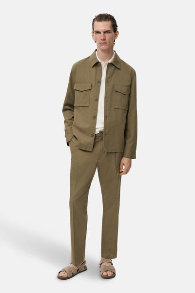 Pantalon kaki de MANGO, porté avec une chemise et des sandales assorties pour un look décontracté.
