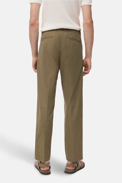 Pantalon kaki de MANGO, coupe droite, avec poches arrière, porté avec un t-shirt blanc et des sandales en cuir.