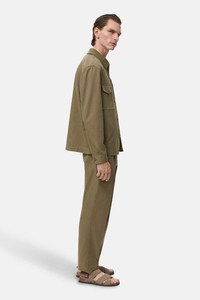 Pantalon kaki de MANGO, porté avec une chemise assortie et des sandales croisées.