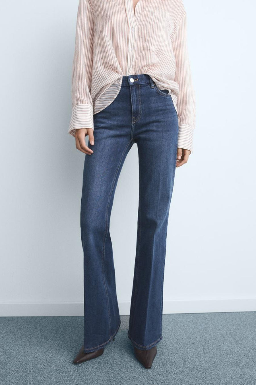Wijde spijkerbroek in donkerblauw denim van MANGO, gedragen met een gestrikte gestreepte blouse.