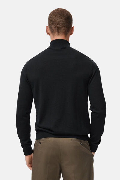 Zwarte coltrui van MANGO, van achteren gezien, gedragen met een bruine broek.
