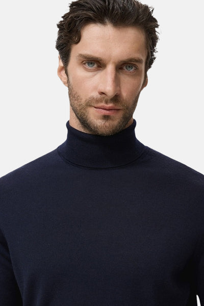 Blauwe coltrui van MANGO, gedragen door een man met een korte baard en bruin haar.