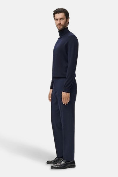 Blauwe trui met ronde hals van MANGO, gedragen met een donkerblauwe broek en zwarte leren schoenen, in zijaanzicht.