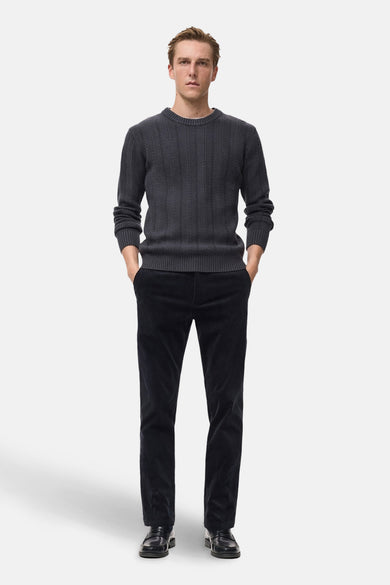 Pantalon de saison bleu marine de MANGO, en velours côtelé, porté avec un pull gris chiné.
