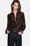 Bruin overhemd met lange mouwen van MANGO, met stippenpatroon en geplooide details, gedragen met een donkerblauwe jeans.